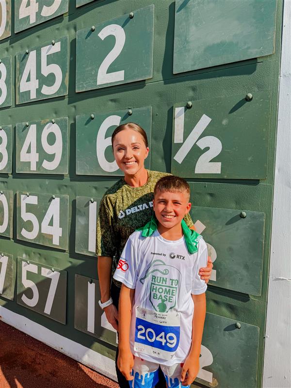 Mother and son smile in front of Green Monster at Fenway Park for Delta Dental at Run to Home Base